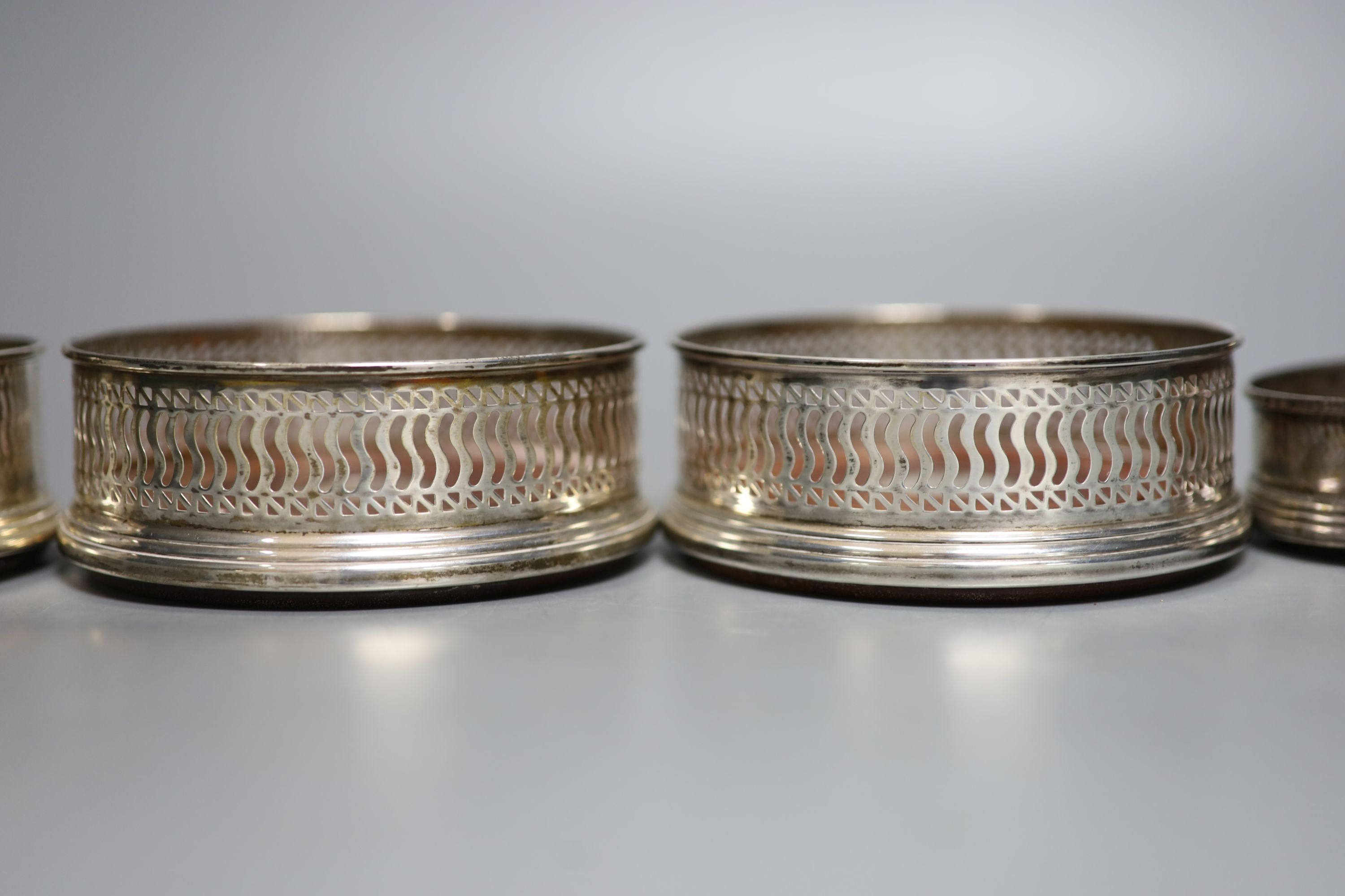 Four assorted modern silver mounted wine coasters, largest diameter 12.2cm.